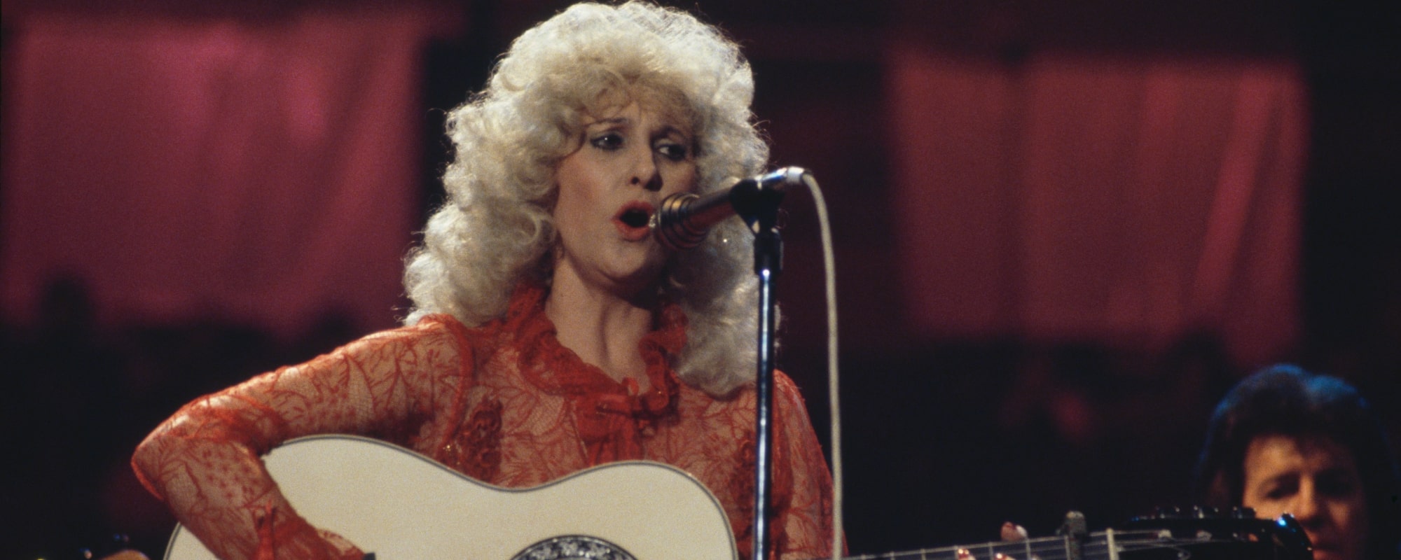 Tammy Wynette (1942-1998), U.S. country music singer-songwriter, singing into a microphone and playing the guitar during a live concert performance at the Country Music Festival, at Wembley Arena, London, England, Great Britain, in April 1981.